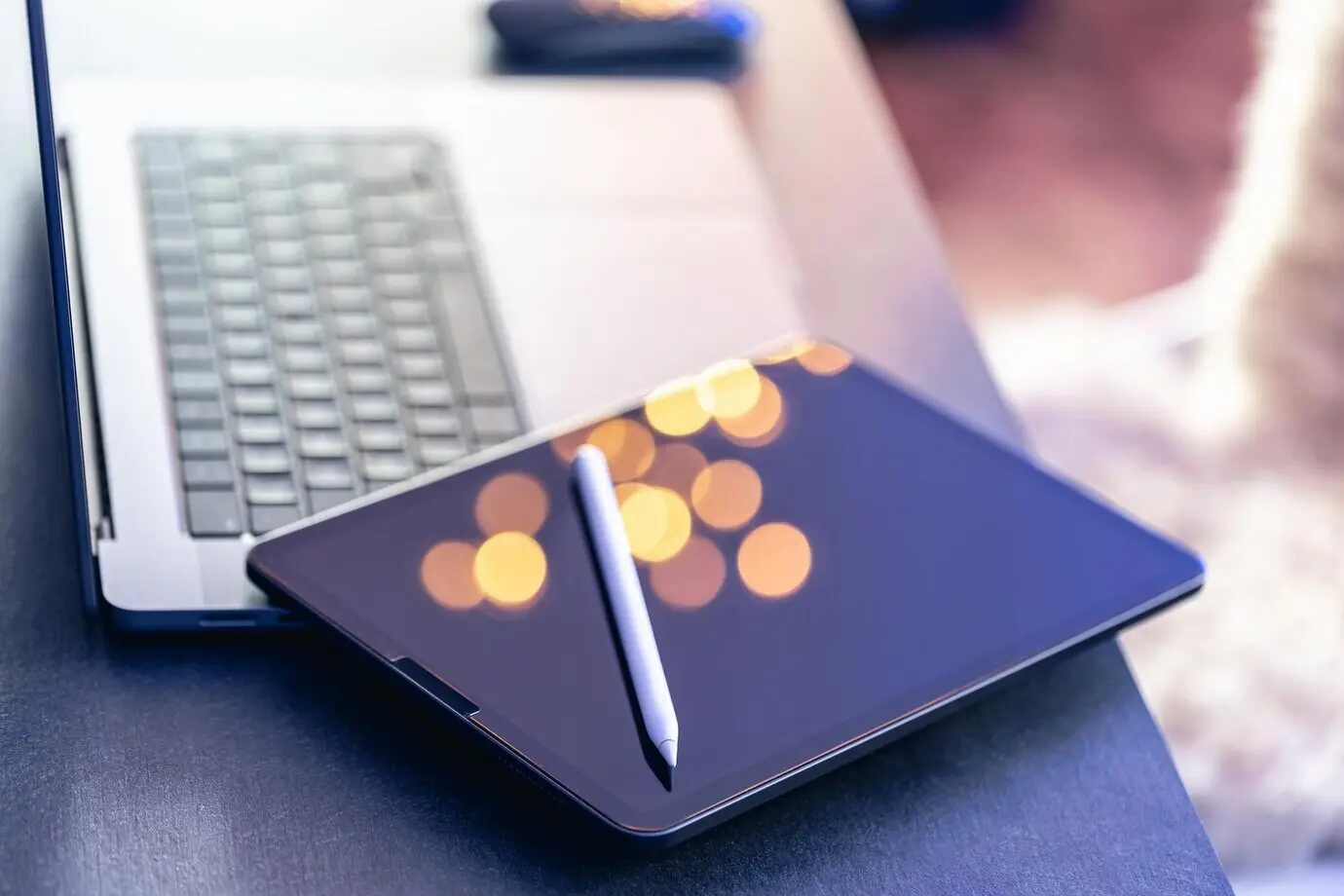 Primer plano de un lápiz óptico para tableta digital y un portátil sobre el escritorio.