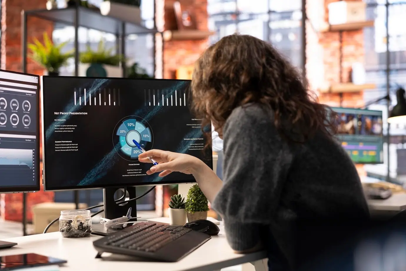 Un analista observa gráficos de una presentación y un panel de control para implementar analítica.